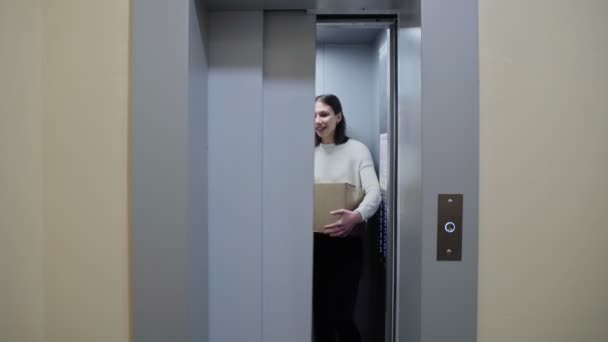 Dua wanita muda keluar dari lift dengan kotak kardus, pindah ke apartemen baru — Stok Video
