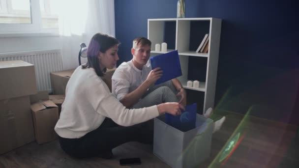 这对快乐的夫妇准备搬出公寓，一家人坐在客厅的地板上检查他们的证件 — 图库视频影像