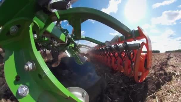 Nahaufnahme eines Traktors mit Eggenanlage, der Boden auf einem bewirtschafteten Feld pflügt, dahinter eine Staubsäule, die Erde für die Anpflanzung neuer Pflanzen vorbereitet — Stockvideo