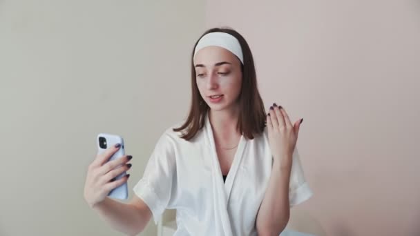 Jonge vrouw met collageen pads onder de ogen neemt selfie video kachels op haar telefoon — Stockvideo