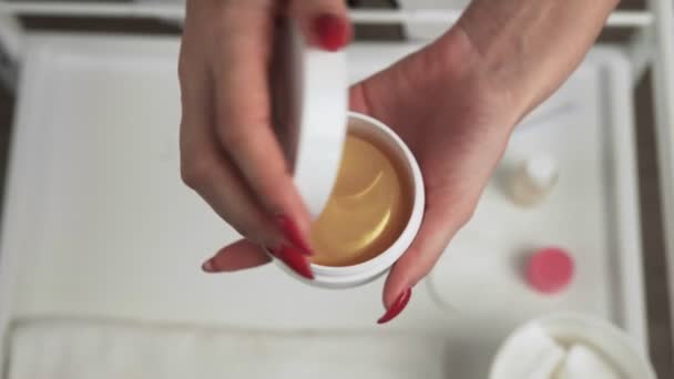 Vista dall'alto di Estetista professionista apre una bottiglia bianca con un tampone di collagene dorato — Video Stock