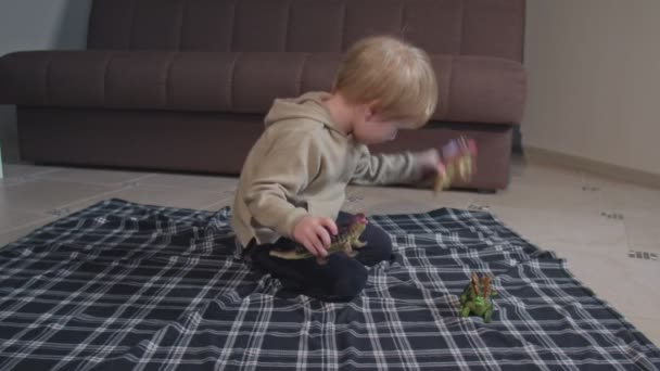 Blond småbarn, leka med dinosaurier hemma — Stockvideo