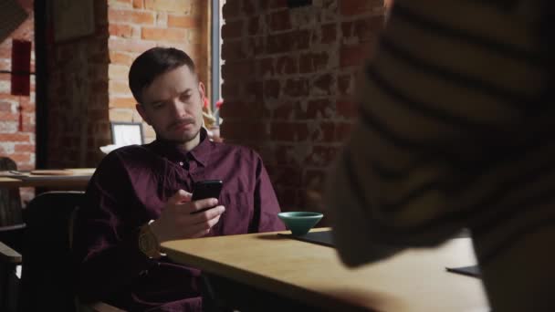 Joven hombre guapo bebiendo té y usando el celular en la cafetería — Vídeos de Stock