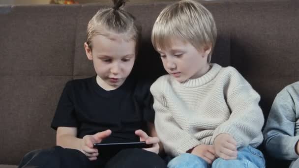 Niedliche Vorschulkinder spielen Spiel auf dem Smartphone zu Hause — Stockvideo