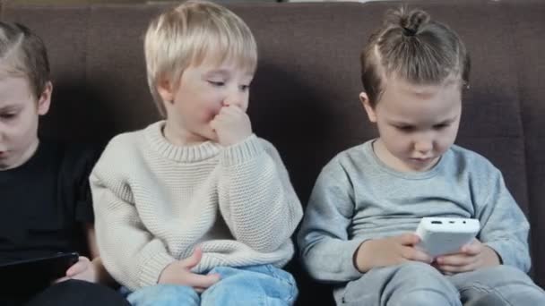 Закройте маленькие улыбающиеся братья, играющие дома в игры на мобильном телефоне. — стоковое видео