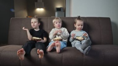 Bir grup çocuk akşamları TV 'de film izleyip patlamış mısır yiyor..