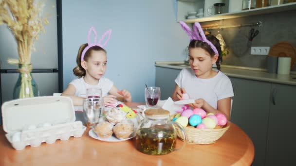 Hermanitas graciosas usando orejas de conejo pintando huevos en el día de Pascua — Vídeo de stock