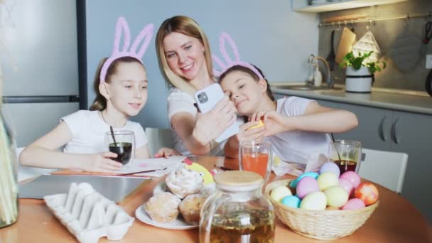 Szczęśliwa rodzina przygotowuje się do Wielkanocy. słodkie małe dziewczynki noszenie królicze uszy robi selfie zdjęcie na Wielkanoc. — Wideo stockowe