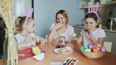Mutlu Paskalyalar. Aileyi Paskalya 'ya hazırlıyorum. Anne ve küçük kızları çay içip kek yiyorlar.