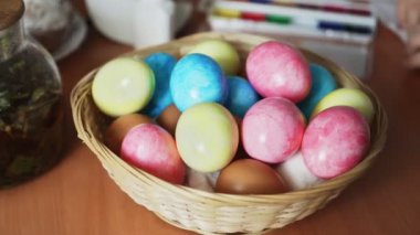 Paskalya için renkli yumurtalar masada Hasır bir sepet üzerinde