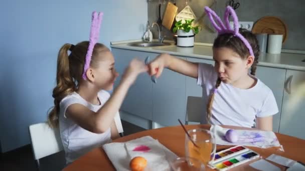 Feliz Pascua. Dos hermanas pintando huevos de Pascua. Felices hijos de familia preparándose para Pascua. Linda niña pequeña con orejas de conejito hacer cinco de altura en la cámara — Vídeo de stock