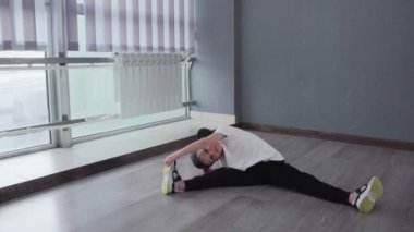 Küçük çocuk breakdance hip-hop dersinden sonra esnemek için egzersiz yapıyor.