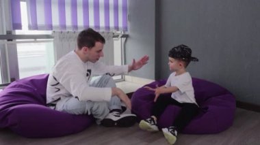 Beyaz tişörtlü ve siyah şapkalı çocuk dans dersinden sonra öğretmeniyle konuşuyor.