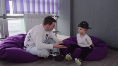 Genç dans öğretmeni, küçük öğrencisine telefonda video gösteriyor.