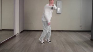 Genç break dansçı stüdyoda hip hop dansı yapıyor. Yakışıklı adam yerde dans hareketleri yapıyor.
