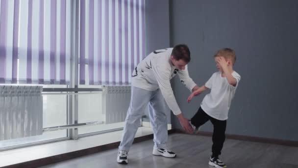 A fehér pólós kisfiú bréktáncot jár a tanárával. — Stock videók