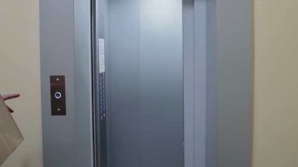 Молодой человек в белой рубашке входит в лифт с картонными коробками, переезжающими в новую квартиру — стоковое видео