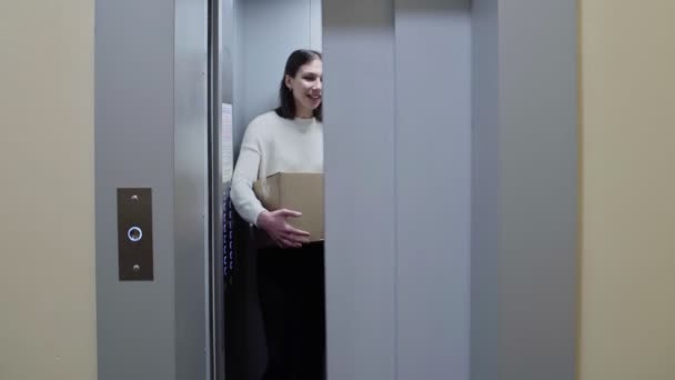 Două tinere care ies din lift cu cutii de carton, se mută într-un nou compartiment — Videoclip de stoc