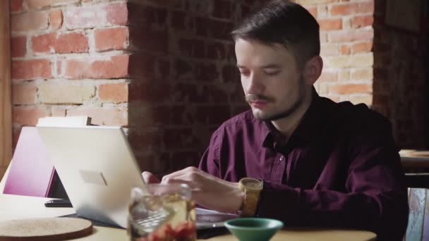 Männliche Buchautoren arbeiten im Café. Junger Mann tippt in Teecafé auf Notizbuch — Stockvideo