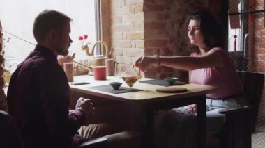 Genç ve mutlu erkek arkadaş ve kız arkadaşın kahvaltıda çay fincanlarıyla sohbet edişinin yan görüntüsü Çin Çay Kafesi 'nde oturuyor.