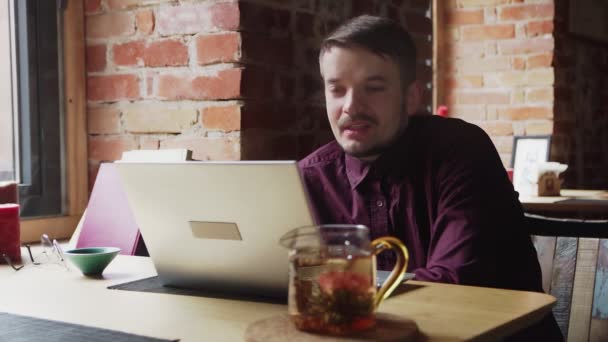 Joven con una camisa roja hablando por Skype en el café — Vídeo de stock