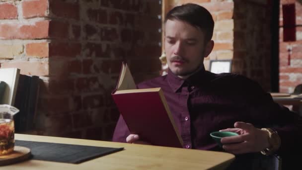 Young guy reading a book and drinking chinese tea at cafe — Stock Video