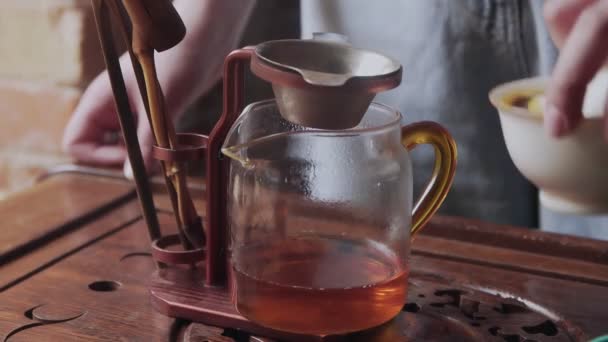Maestro vierte té verde de gaiwan a hervidor de agua de vidrio mientras la ceremonia china — Vídeos de Stock