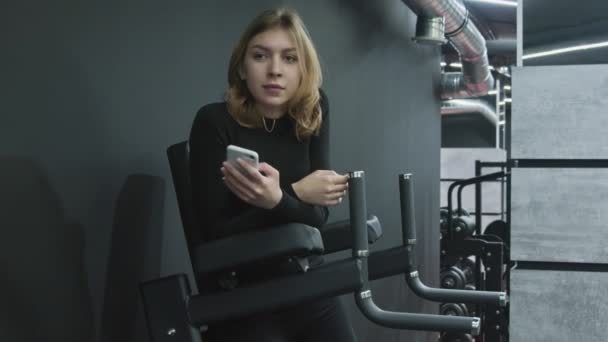 Молода приваблива фітнес жінка використовує телефон і розслабляється після фізичних вправ — стокове відео