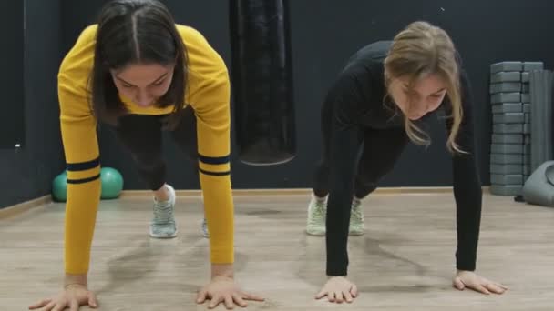 Dos jóvenes mujeres Fitness haciendo tablones dinámicos en el gimnasio. — Vídeos de Stock