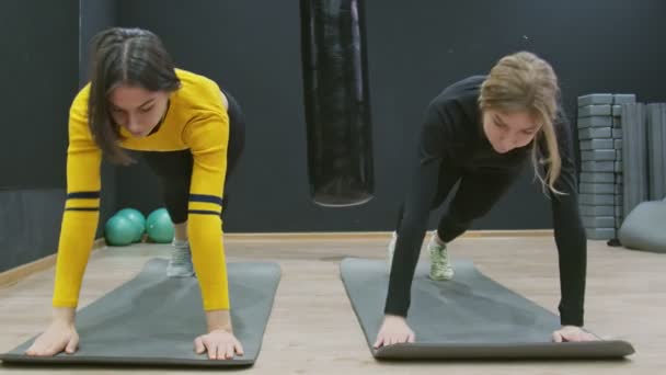 Zwei junge Fitness-Frauen beim dynamischen Planken im Fitnessstudio. — Stockvideo