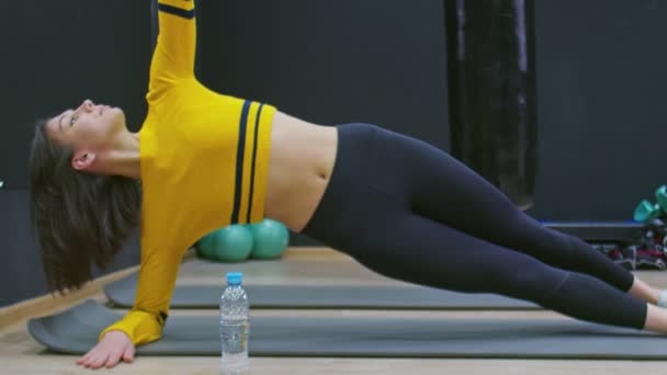 Top kilátás Fitness nő csinál oldalsó deszkák edzés a tornateremben. Női főgyakorlatok a fitnesz stúdióban. — Stock videók