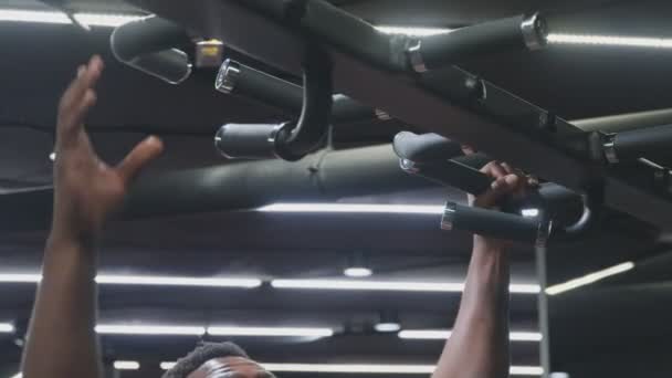 Крупный план красивого афро-американского мускулистого человека, делающего подтягивания на горизонтальной полосе — стоковое видео