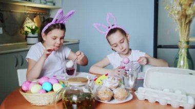 Küçük kızlar tavşan kulağı takıp Paskalya günü yumurta boyuyorlar.