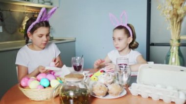 Paskalya günü tavşan kulağı takan komik kız kardeşler yumurta boyuyor.