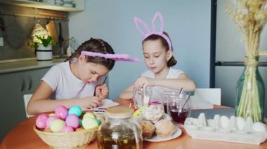Küçük kızlar yumurta boyar. Yumurtalara Paskalya desenleri çiziyorlar..