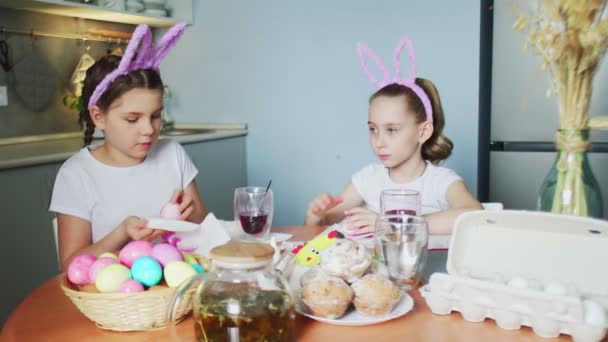 Paskalya günü tavşan kulağı takan komik kız kardeşler yumurta boyuyor. — Stok video