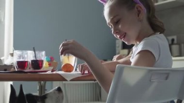 Güzel küçük kız mutfakta güzel bir köpekle oynuyor.