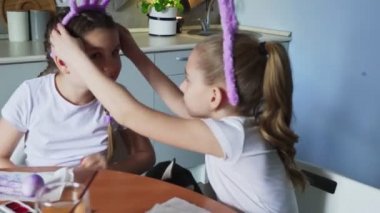 Mutlu aile Paskalya için hazırlanıyor. Şirin küçük kız kardeşinin üzerine pembe bir tavşan kulağı takıyor.