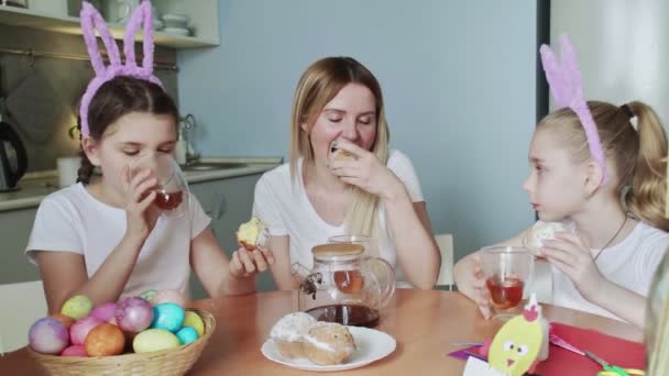 Buona Pasqua. Preparare la famiglia per Pasqua. Mamma e le sue piccole figlie bevono tè e mangiano muffin — Video Stock