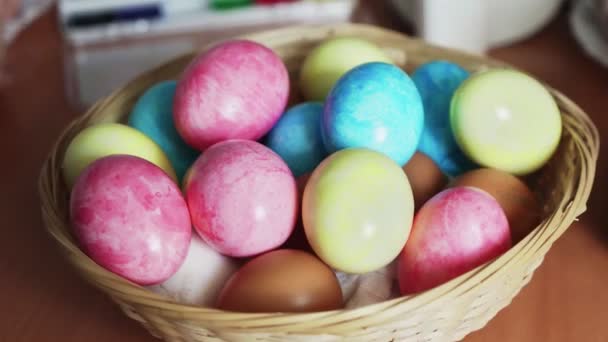 Húsvéti színes tojások egy fonott kosárban az asztalon — Stock videók