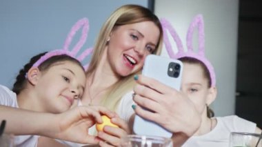 Mutlu aile Paskalya için hazırlanıyor. Anneleri tavşan kulağı takan sevimli küçük kızlar Paskalya gününde selfie çekiyorlar..