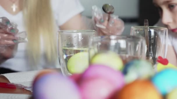 З Великоднем. Приготувати сім'ю на Великдень. Жінка з маленькими дівчатами фарбує великодні яйця.. — стокове відео