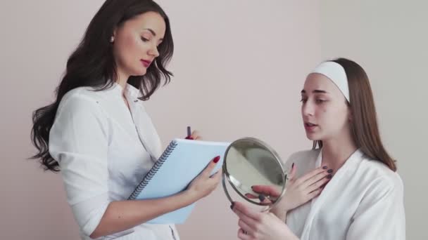 La mujer visita al joven médico cosmetólogo. El médico consulta con el paciente — Vídeo de stock