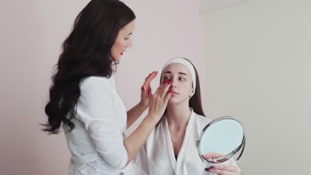 Женщина-косметолог апплицирует коллагеновые прокладки на глаза женщине-клиенту в салоне красоты. — стоковое видео