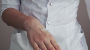 Profesyonel güzellik uzmanına yakın çekim. Ellerine nasıl vücut losyonu sürüleceğini gösteriyor.