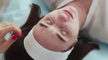 Kozmetik uzmanının en iyi görüşü güzellik salonundaki kadın müşteri yüzüne losyon sürmesi..