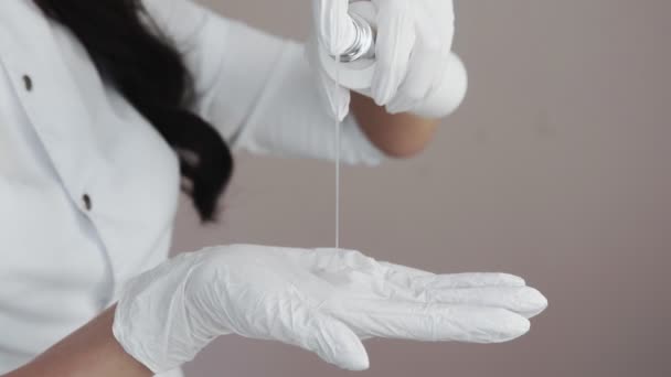 Close-up van professionele schoonheidsspecialiste knijpt de crème op haar hand in witte handschoenen — Stockvideo