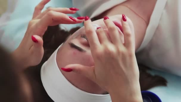 Vista dall'alto del cosmetologo applica rilievi di collagene sotto i suoi occhi sulla cliente donna nel salone di bellezza della clinica. — Video Stock