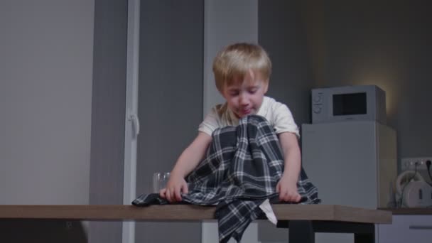 小さな男の子とともにblankit座ってテーブルの上で夕食後に現代的なキッチン. — ストック動画