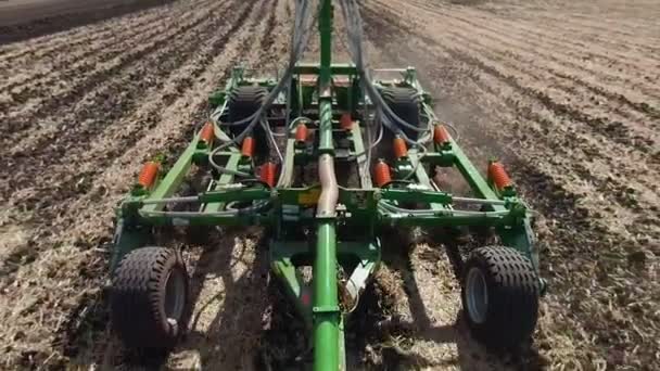 Vue arrière du tracteur avec système de herse labourant sur un champ agricole cultivé, pilier de pistes de poussière derrière, préparation du sol pour la plantation de nouvelles cultures — Video